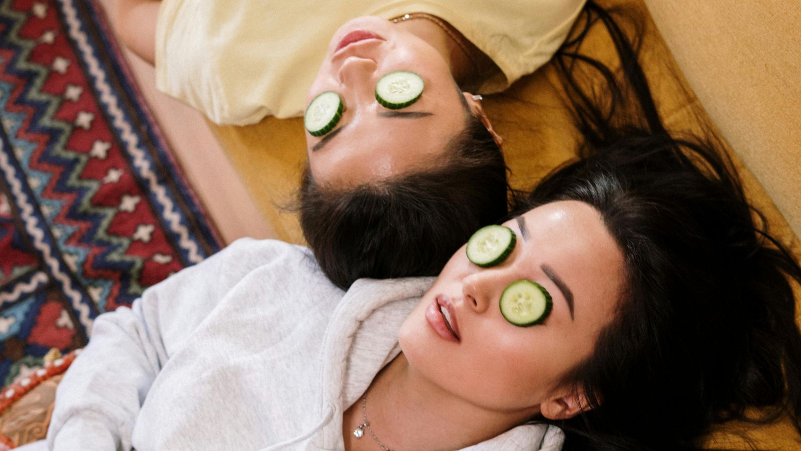 2.6K Organic Traffic for a Skincare Website 20 Two people are lying down on a couch with their heads at opposite ends, wearing casual clothes. Each has cucumber slices placed over their eyes, indulging in a skincare routine that suggests a relaxing or spa-like atmosphere. A colorful carpet is partially visible to the side. for Growing Organic Traffic to 2.6K for a Skincare Website Through SEO case study